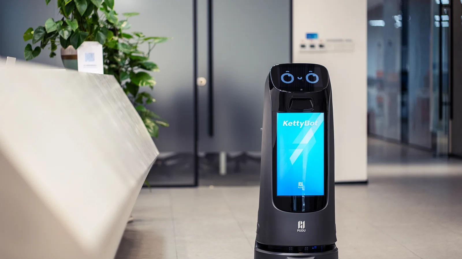 KettyBot Pro moving through a busy wood panelled lobby